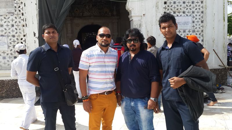 Group of four men posing outside a historic monument