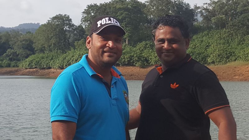 Two men posing by a lake