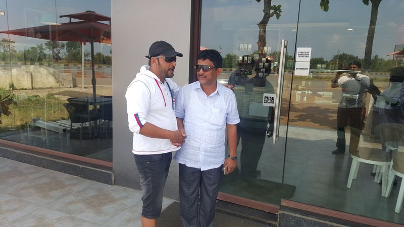Two men posing outside a glass-fronted building